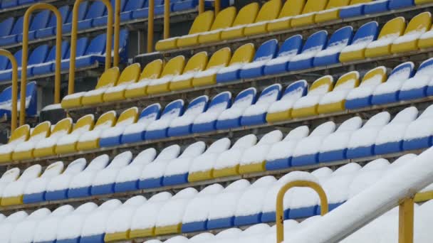 Żółte niebieskie krzesła pokryte śniegiem na stadionie — Wideo stockowe