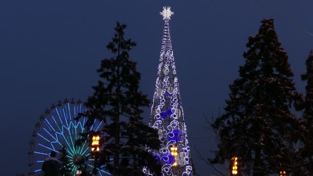 Rueda de la fortuna y un árbol de Navidad con luces — Vídeos de Stock