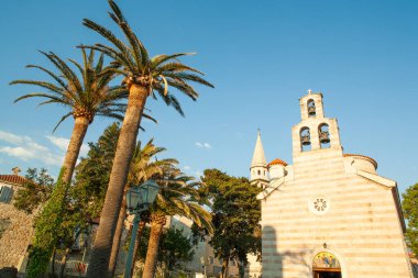 Beautiful view of the St. Nicholas orthodox christian church in Old Town Budva in Montenegro on a sunny day next to palm trees