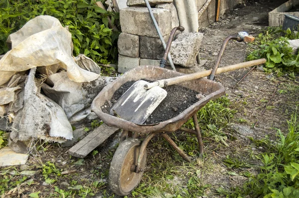 Toprak ve bir kürek ile el arabası. Rus köy.