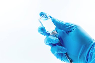 Aşı kavramı, doktorun beyaz aşı şişesi ve siyah arka planda izole edilmiş fotokopi alanı olan mavi eldivenin elinde.