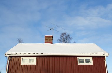 Çatısı karlı kırmızı ev.