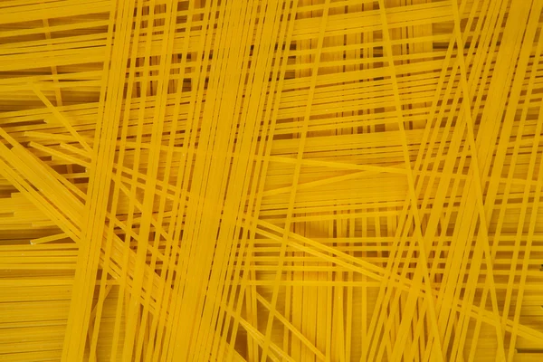 Sfondo spaghetti. Spaghetti lunghi gialli su fondo nero. Pasta sottile disposti in file. Pasta gialla italiana. Spaghetti lunghi. Carta da parati spaghetti grezzi . — Foto Stock