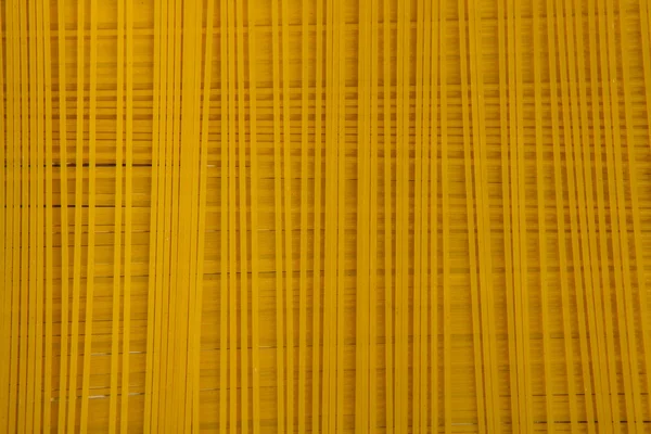 Spaghetti background. Yellow long spaghetti on black background. Thin pasta arranged in rows. Yellow italian pasta. Long spaghetti. Raw spaghetti wallpaper. — Stock Photo, Image