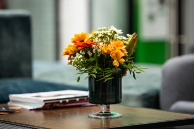 Modern ofiste vazo dolusu çiçekli çalışma masası. Modern bir odadaki bir masanın üzerinde bir buket çiçek..