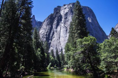 Yosemite Vadisi 'nin muhteşem manzarası. Yazın mavi gökyüzü ile güneşli güzel bir günde, kayalar ve nehirle birlikte, Yosemite Ulusal Parkı, Kaliforniya, ABD