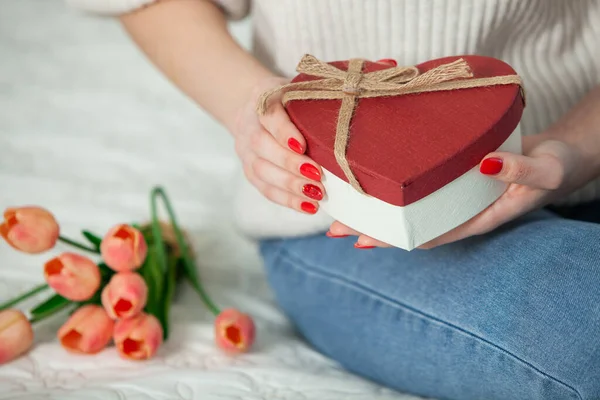 Beautiful girl open red heart gift box. Valentine\'s day. Happy Birthday. Girl receives a gift at home.