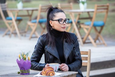 Siyah deri kıyafetler ve gözlük takmış güzel bir Rus kızı. Kentsel arka planda rock tarzı Avrupalı kadın.