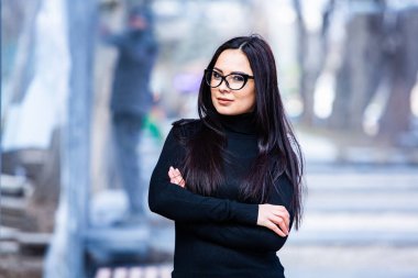 Siyah deri kıyafetler ve gözlük takmış güzel bir Rus kızı. Kentsel arka planda rock tarzı Avrupalı kadın.