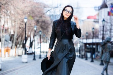 Siyah deri kıyafetler ve gözlük takmış güzel bir Rus kızı. Kentsel arka planda rock tarzı Avrupalı kadın.