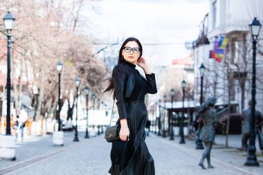 Siyah deri kıyafetler ve gözlük takmış güzel bir Rus kızı. Kentsel arka planda rock tarzı Avrupalı kadın.