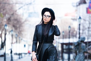 Siyah deri kıyafetler ve gözlük takmış güzel bir Rus kızı. Kentsel arka planda rock tarzı Avrupalı kadın.