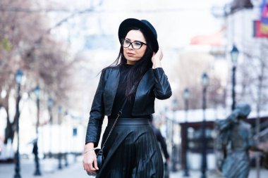 Siyah deri kıyafetler ve gözlük takmış güzel bir Rus kızı. Kentsel arka planda rock tarzı Avrupalı kadın.