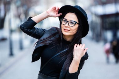 Siyah deri kıyafetler ve gözlük takmış güzel bir Rus kızı. Kentsel arka planda rock tarzı Avrupalı kadın.