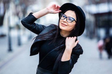 Siyah deri kıyafetler ve gözlük takmış güzel bir Rus kızı. Kentsel arka planda rock tarzı Avrupalı kadın.