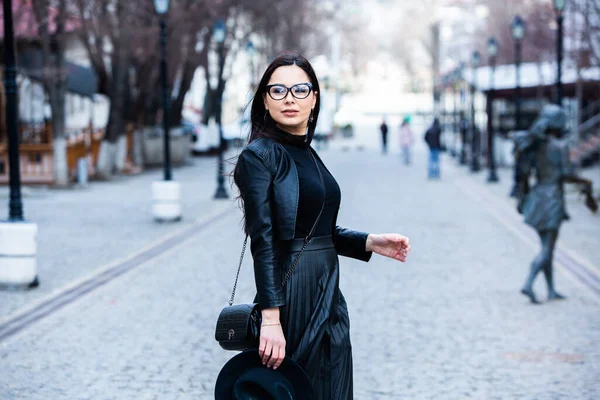 Siyah deri kıyafetler ve gözlük takmış güzel bir Rus kızı. Kentsel arka planda rock tarzı Avrupalı kadın.
