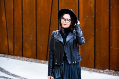 Siyah deri kıyafetler ve gözlük takmış güzel bir Rus kızı. Kentsel arka planda rock tarzı Avrupalı kadın.