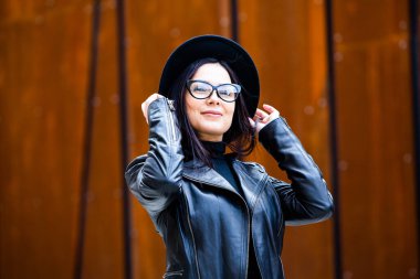 Siyah deri kıyafetler ve gözlük takmış güzel bir Rus kızı. Kentsel arka planda rock tarzı Avrupalı kadın.