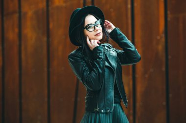 Siyah deri kıyafetler ve gözlük takmış güzel bir Rus kızı. Kentsel arka planda rock tarzı Avrupalı kadın.