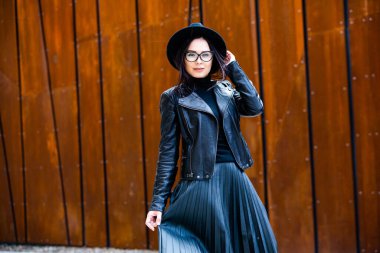 Siyah deri kıyafetler ve gözlük takmış güzel bir Rus kızı. Kentsel arka planda rock tarzı Avrupalı kadın.