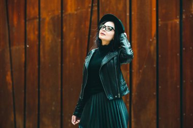 Siyah deri kıyafetler ve gözlük takmış güzel bir Rus kızı. Kentsel arka planda rock tarzı Avrupalı kadın.