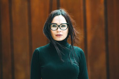 Güzel seksi manken kadın portresi, gözlük takıyor. Gözlüklü, siyah elbiseli, şık bir kadın kameraya bakıyor.