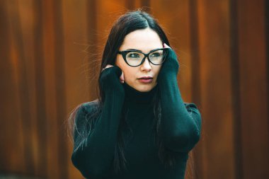 Güzel seksi manken kadın portresi, gözlük takıyor. Gözlüklü, siyah elbiseli, şık bir kadın kameraya bakıyor.