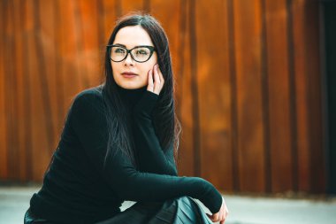 Güzel seksi manken kadın portresi, gözlük takıyor. Gözlüklü, siyah elbiseli, şık bir kadın kameraya bakıyor.