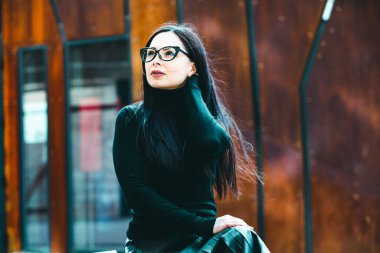 Güzel seksi manken kadın portresi, gözlük takıyor. Gözlüklü, siyah elbiseli, şık bir kadın kameraya bakıyor.