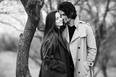 Genç ve şık bir çiftin güzel şehvetli portresi. Parkta yağmurluk giymiş güzel esmer bir çiftin resmi. Mutlu aile