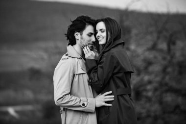 Genç ve şık bir çiftin güzel şehvetli portresi. Parkta yağmurluk giymiş güzel esmer bir çiftin resmi. Mutlu aile