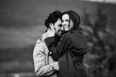 Genç ve şık bir çiftin güzel şehvetli portresi. Parkta yağmurluk giymiş güzel esmer bir çiftin resmi. Mutlu aile