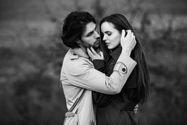 Genç ve şık bir çiftin güzel şehvetli portresi. Parkta yağmurluk giymiş güzel esmer bir çiftin resmi. Mutlu aile