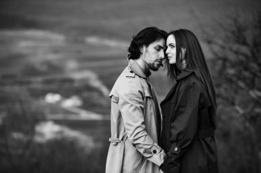 Genç ve şık bir çiftin güzel şehvetli portresi. Parkta yağmurluk giymiş güzel esmer bir çiftin resmi. Mutlu aile