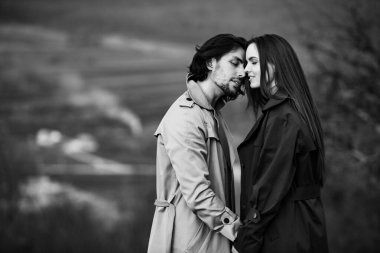 Genç ve şık bir çiftin güzel şehvetli portresi. Parkta yağmurluk giymiş güzel esmer bir çiftin resmi. Mutlu aile