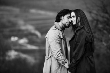 Genç ve şık bir çiftin güzel şehvetli portresi. Parkta yağmurluk giymiş güzel esmer bir çiftin resmi. Mutlu aile