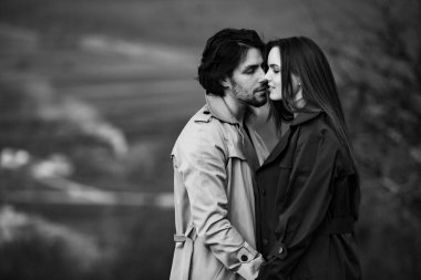 Genç ve şık bir çiftin güzel şehvetli portresi. Parkta yağmurluk giymiş güzel esmer bir çiftin resmi. Mutlu aile