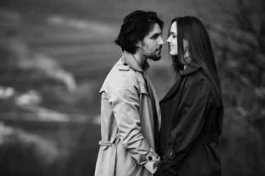 Genç ve şık bir çiftin güzel şehvetli portresi. Parkta yağmurluk giymiş güzel esmer bir çiftin resmi. Mutlu aile