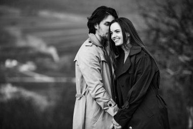 Genç ve şık bir çiftin güzel şehvetli portresi. Parkta yağmurluk giymiş güzel esmer bir çiftin resmi. Mutlu aile