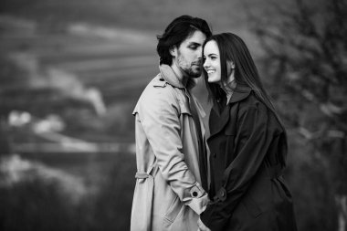 Genç ve şık bir çiftin güzel şehvetli portresi. Parkta yağmurluk giymiş güzel esmer bir çiftin resmi. Mutlu aile