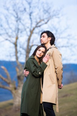 Genç ve şık bir çiftin güzel şehvetli portresi. Parkta yağmurluk giymiş güzel esmer bir çiftin resmi. Mutlu aile