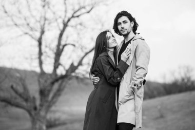 Genç ve şık bir çiftin güzel şehvetli portresi. Parkta yağmurluk giymiş güzel esmer bir çiftin resmi. Mutlu aile