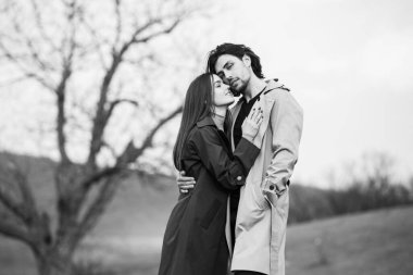 Genç ve şık bir çiftin güzel şehvetli portresi. Parkta yağmurluk giymiş güzel esmer bir çiftin resmi. Mutlu aile