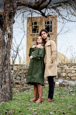 Genç ve şık bir çiftin güzel şehvetli portresi. Parkta yağmurluk giymiş güzel esmer bir çiftin resmi. Mutlu aile