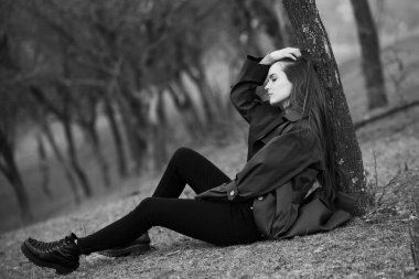 Soğuk havada yağmurluk giyen güzel bir kadın resmi. Bahar doğasında Düşünen Avrupalı kız.