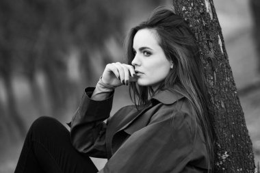 Soğuk havada yağmurluk giyen güzel bir kadın resmi. Bahar doğasında Düşünen Avrupalı kız.