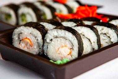 Japon yemekleri plastik kutuda yuvarlanıyor. Sushi plastik bir paketin içinde, beyaz bir arka planda izole edilmiş. Paket veya suşi servisi için suşi..