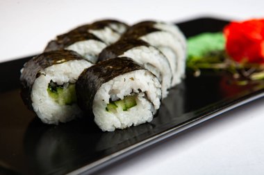 Japon yemekleri plastik kutuda yuvarlanıyor. Sushi plastik bir paketin içinde, beyaz bir arka planda izole edilmiş. Paket veya suşi servisi için suşi..