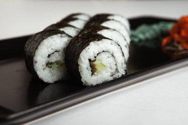 Japon yemekleri plastik kutuda yuvarlanıyor. Sushi plastik bir paketin içinde, beyaz bir arka planda izole edilmiş. Paket veya suşi servisi için suşi..
