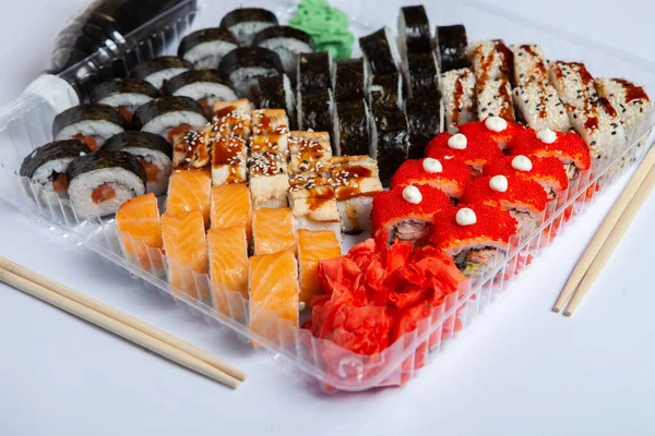 プラスチック製の箱に日本食のロール 白い背景に閉じ込められたプラスチック製のパッケージにセットされた寿司 寿司の持ち帰りや寿司の配達 — ストック写真